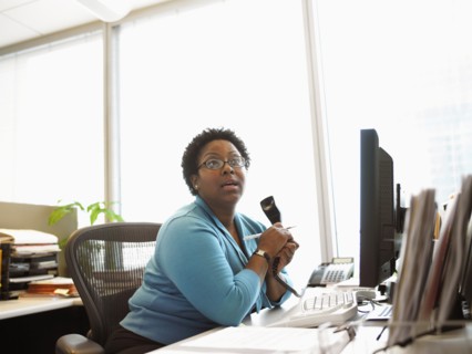 Businesswoman sitting at desk with telephone
