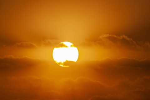 Sun with orange clouds in sunset sky