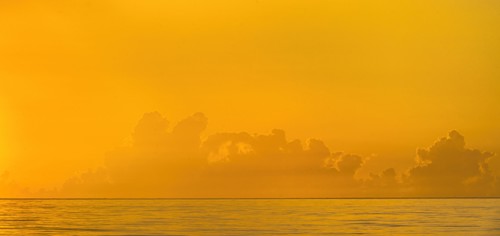 Golden sunrise clouds over calm ocean