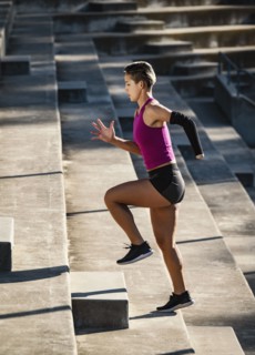 Woman with amputated hand jogging up steps