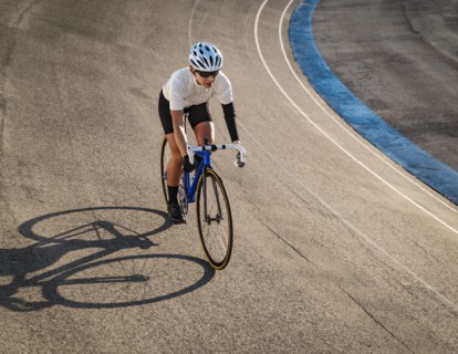 Athletic woman with amputated hand cycling on track