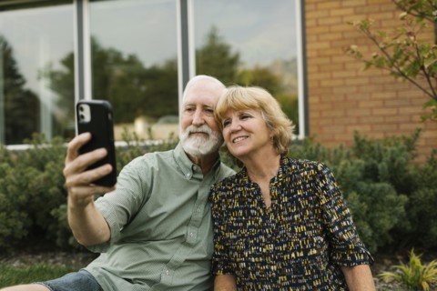 Smiling senior couple taking selfie in backyard