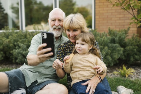 Smiling grandparents taking selfie with granddaughter