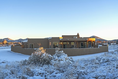Pueblo style house in snow covered landscape at sunset