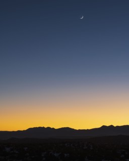 Jemez Mountains at dusk with crescent moon on sky