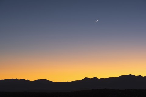 Jemez Mountains at dusk with crescent moon on sky
