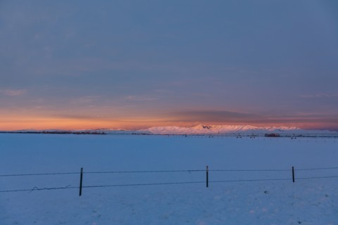 USA, Idaho, Bellevue, Snow covered field with hills in distance at sunrise