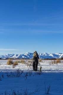 Senior blonde woman snow shoeing in snow covered landscape