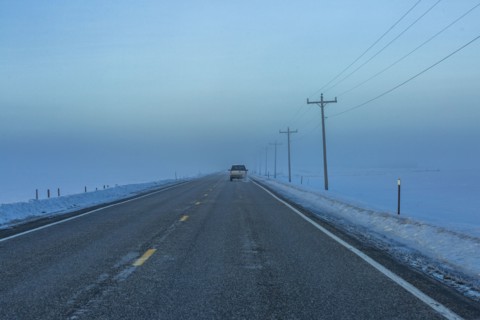 Car heading into fogbank along Highway 20 in winter