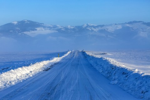 Snow covered rural road leading to mountains