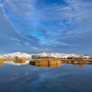 Calm river with snow covered hills in background