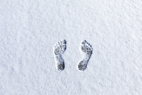 Overhead view of bare footprints in fresh snow