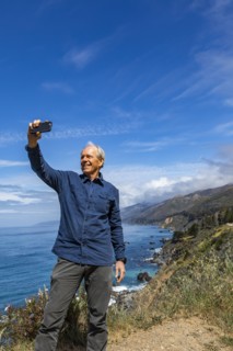 Smiling senior man taking selfie at Big Sur coast