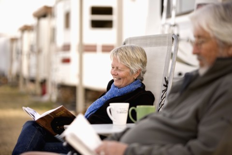 Senior couple reading book outside mobile home