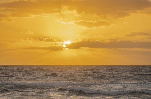 Golden sky with sun and calm ocean at sunset