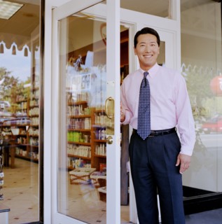 Portrait of store owner opening door to pharmacy
