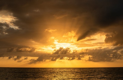 Orange clouds over ocean at sunrise