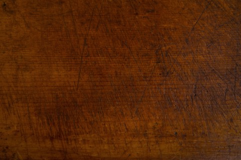 Close-up of worn antique cutting board with knife cut marks