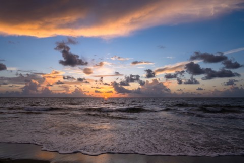 Dramatic sunrise sky above ocean and beach