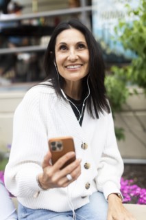 Smiling woman using phone and headphones