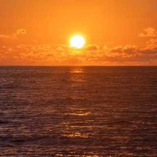 Sun rising above calm ocean