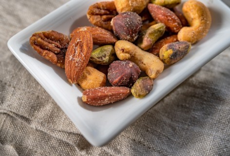 Close-up of small dish of assorted nuts on linen table cloth