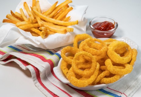 Fried onion rings and French fries with ketchup on tablecloth