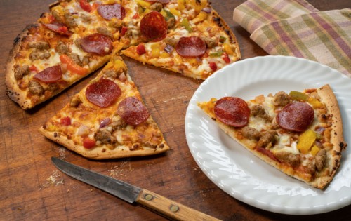 Cut up pizza with one slice of on plate