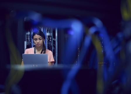 Female technician using laptop in server room