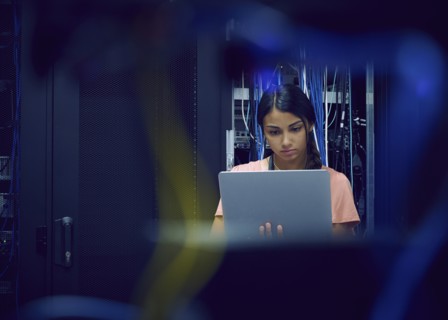 Female technician using laptop in server room
