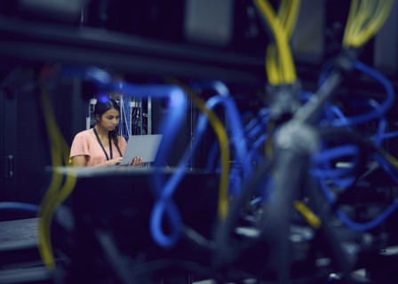 Female technician using laptop in server room