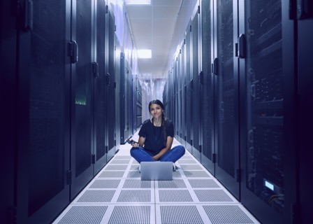 Portrait of female technician sitting on floor in server room