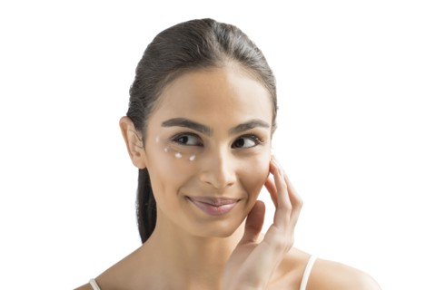 Portrait of smiling young woman applying face cream
