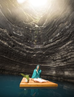 Woman sitting on wooden raft in cenote