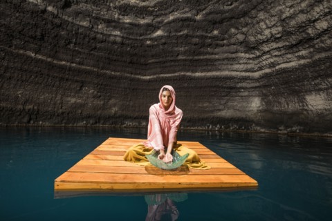 Woman sitting on wooden raft in cenote