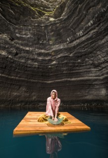 Woman sitting on wooden raft in cenote