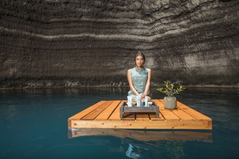 Beautiful woman kneeling on wooden raft on pond