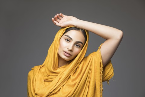 Studio portrait of beautiful woman wearing gold headscarf