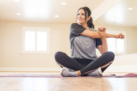 Woman sitting on floor and stretching in dance studio