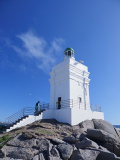 Woman climbing white lighthouse on sea coast