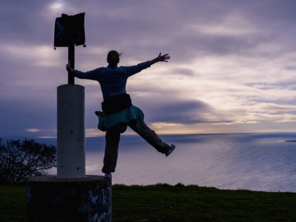 Woman standing on sign post on sea coast
