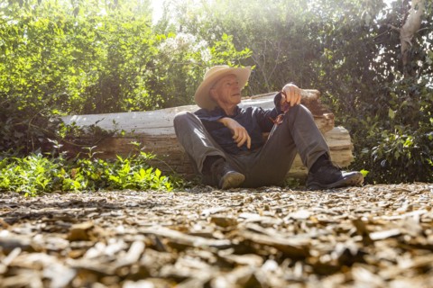 Senior man resting next to fallen tree