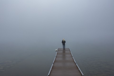 Back view of senior woman standing on jetty in morning
