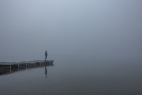 Woman standing on jetty in morning by lake
