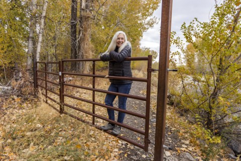 Senior blonde woman leaning on ranch gate
