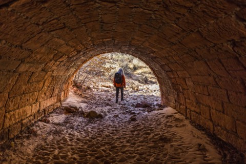 Female hiker walking through tunnel