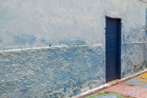 Colorful blue walls and old door in alleyway in medina