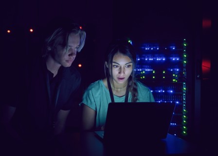 Technicians using laptop in server room
