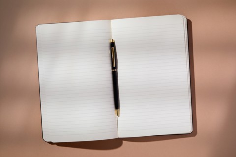 Pen in open notebook on brown background