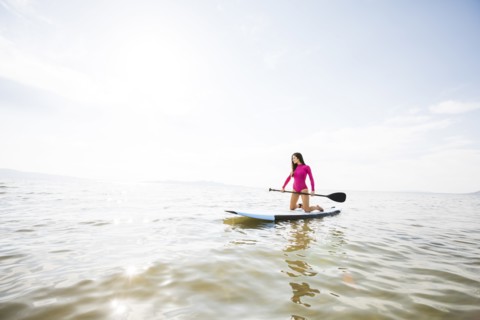 Woman kneeling on paddleboar in lake